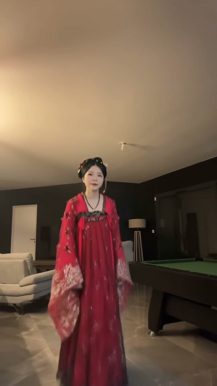 AI-generated woman in red embroidered Hanfu dancing in a living room beside a pool table.
