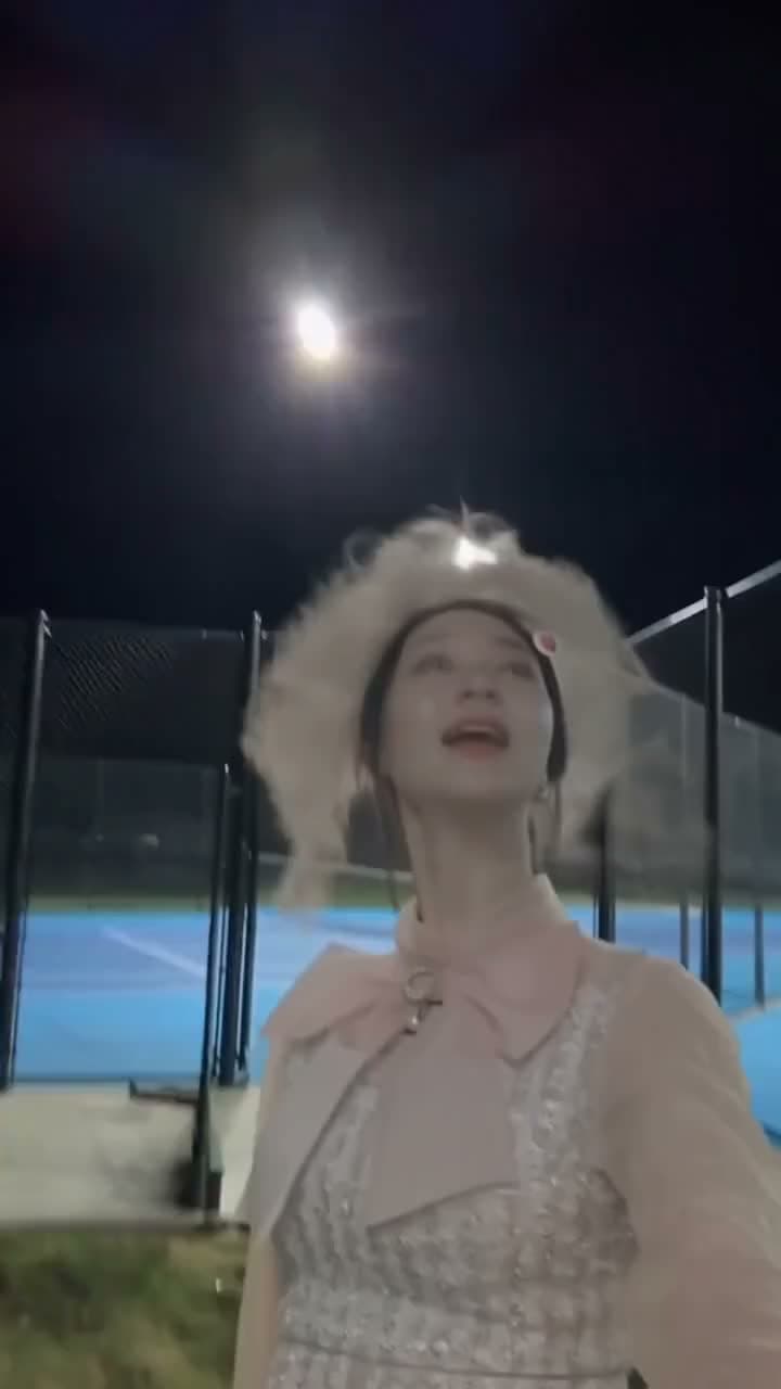 A performer looking toward a moving phone camera in a vertical singing selfie.