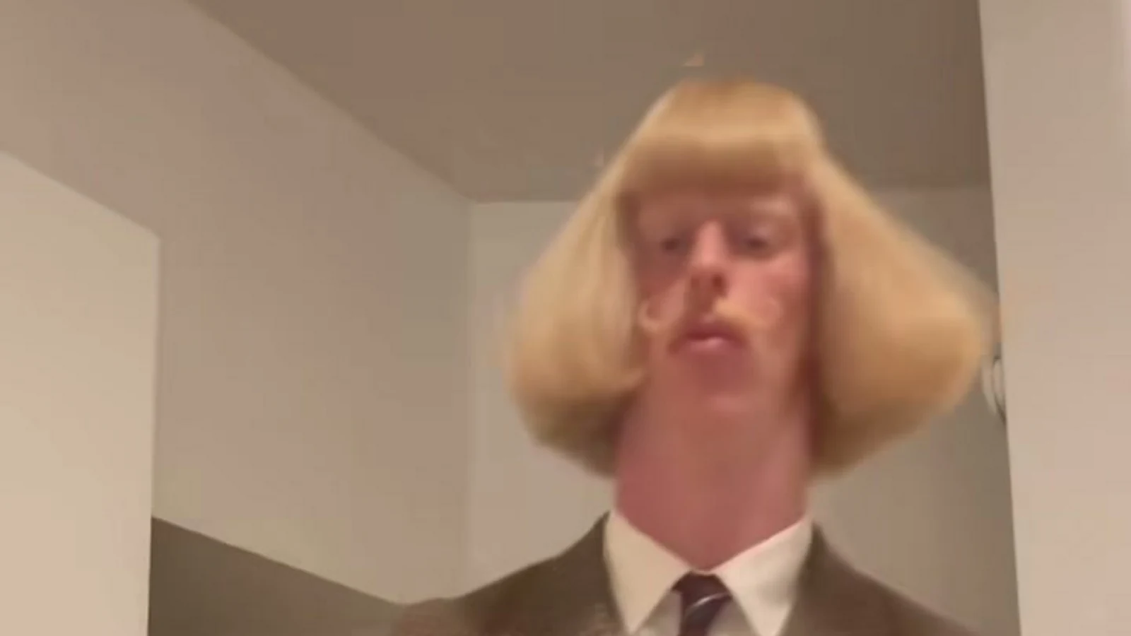 Jean Phil’s blond bob, moustache, shirt and tie in a landscape crop of the shadowboxing reference.