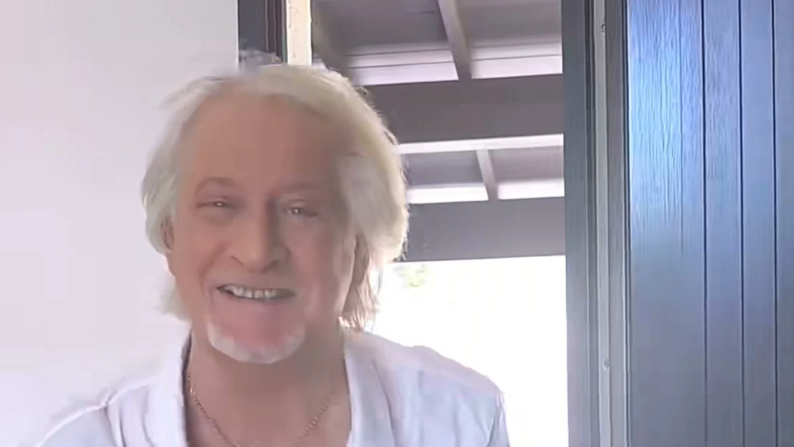 Landscape crop of Patrick Sébastien speaking from an open doorway in his Toc Toc response video.