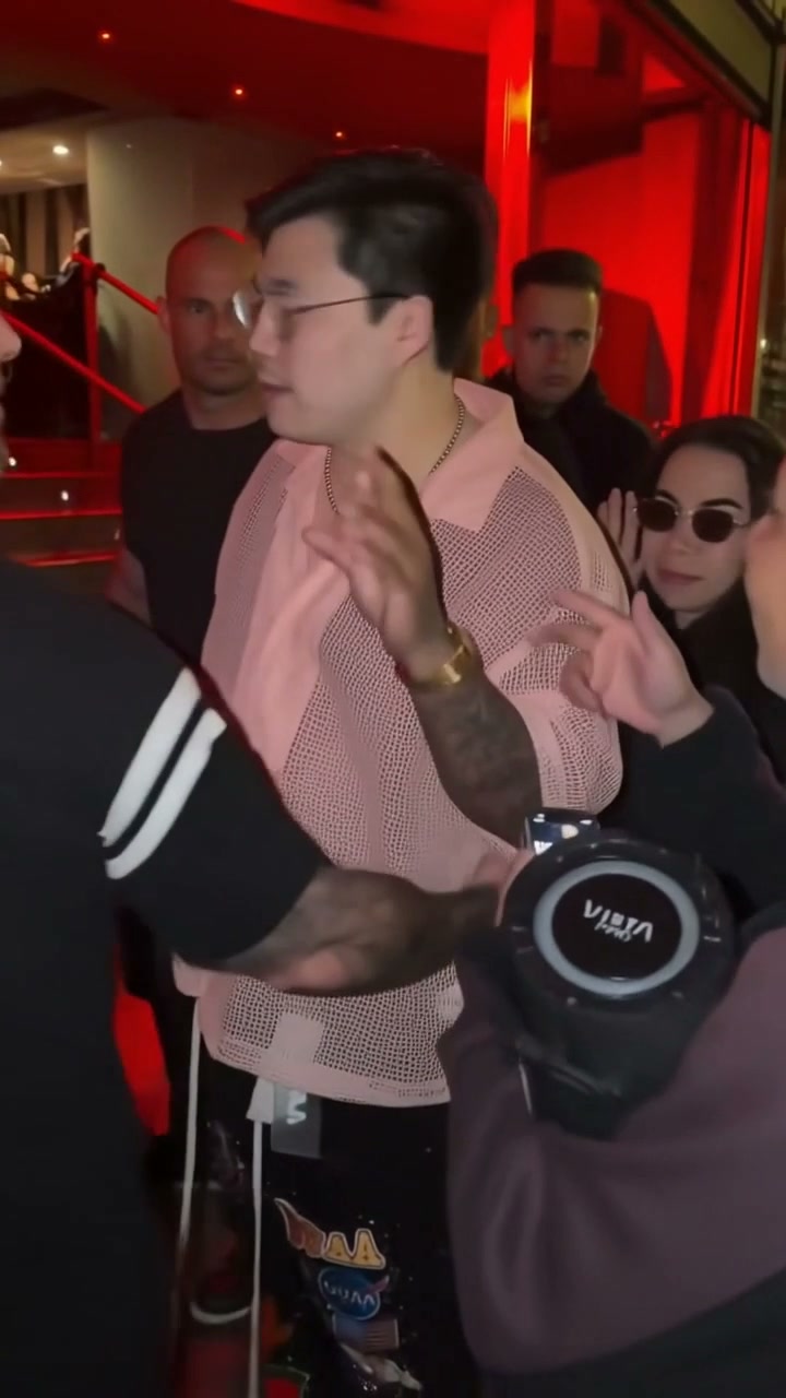 AI-generated adult lead performer in a pale pink shirt in a red-lit street performance scene.